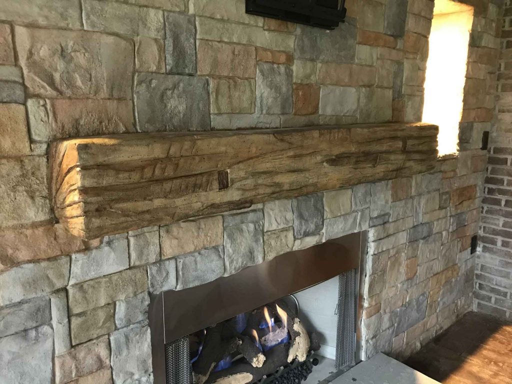 An interior residential decorative concrete wall façade featuring a fireplace, hearth and mantle with furniture.